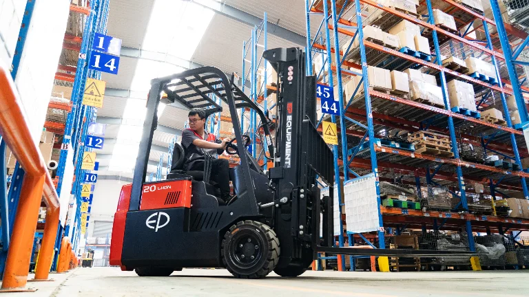 elektrische heftruck rijdend langs stellingen