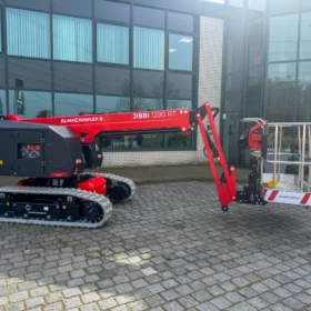zijaanzicht rups telescoophoogwerker met bedrijfspand erachter